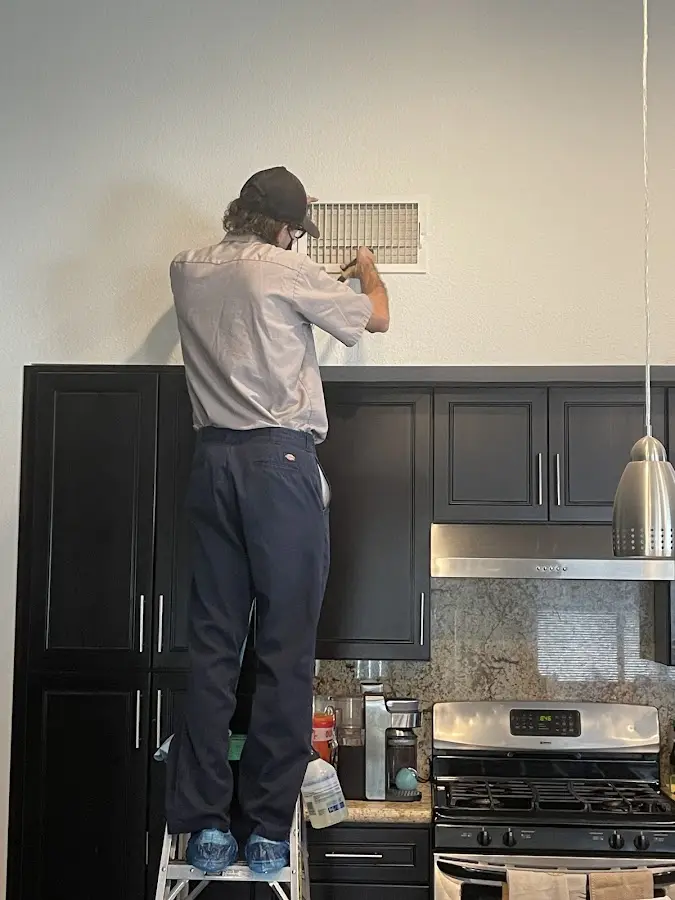 Technician inspecting an air vent during HVAC service in Palm Beach